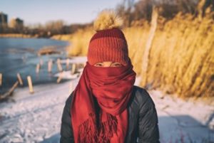 Femme debout à l'extérieur portant un foulard enroulé sur sa bouche et son nez