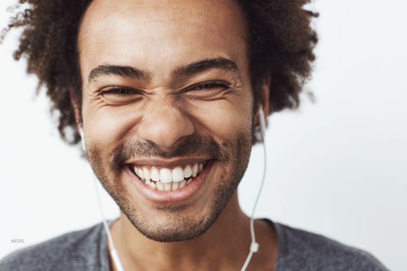 Un homme heureux aux dents blanches sourit.